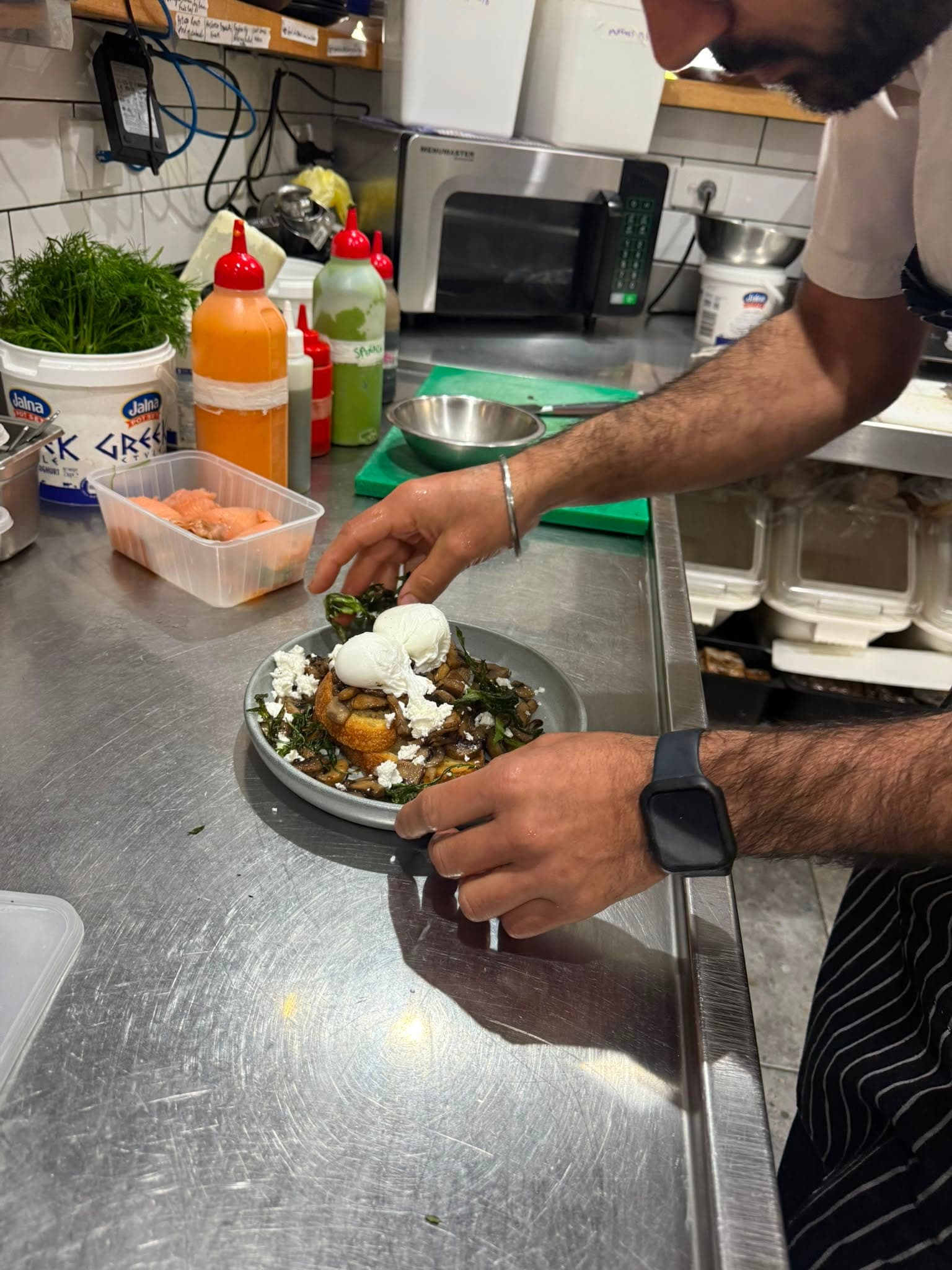 A chef preparing a fresh dish in the open kitchen at The Waterboy Cafe