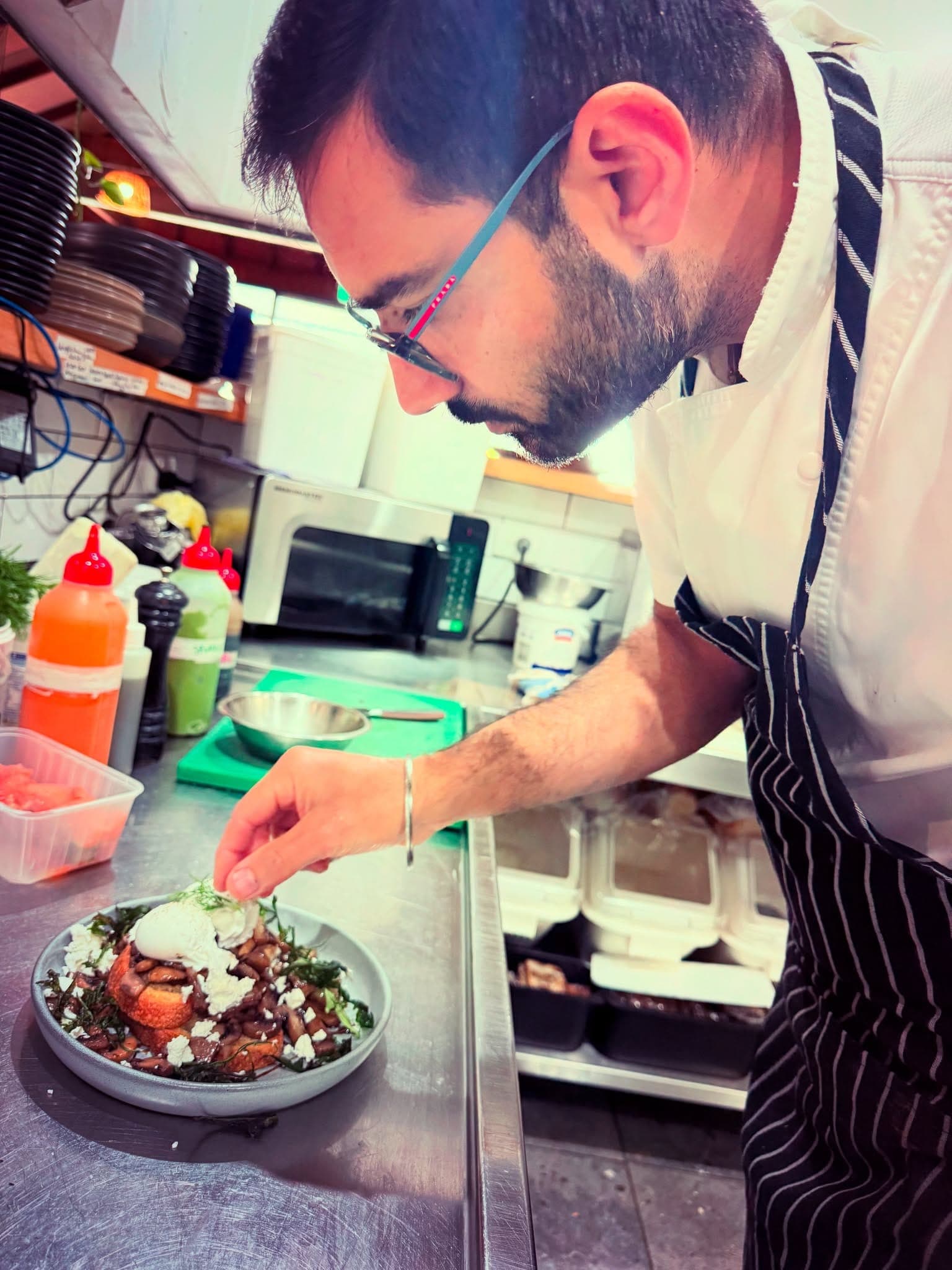 One of the owners of The Waterboy Cafe preparing food by hand in the kitchen