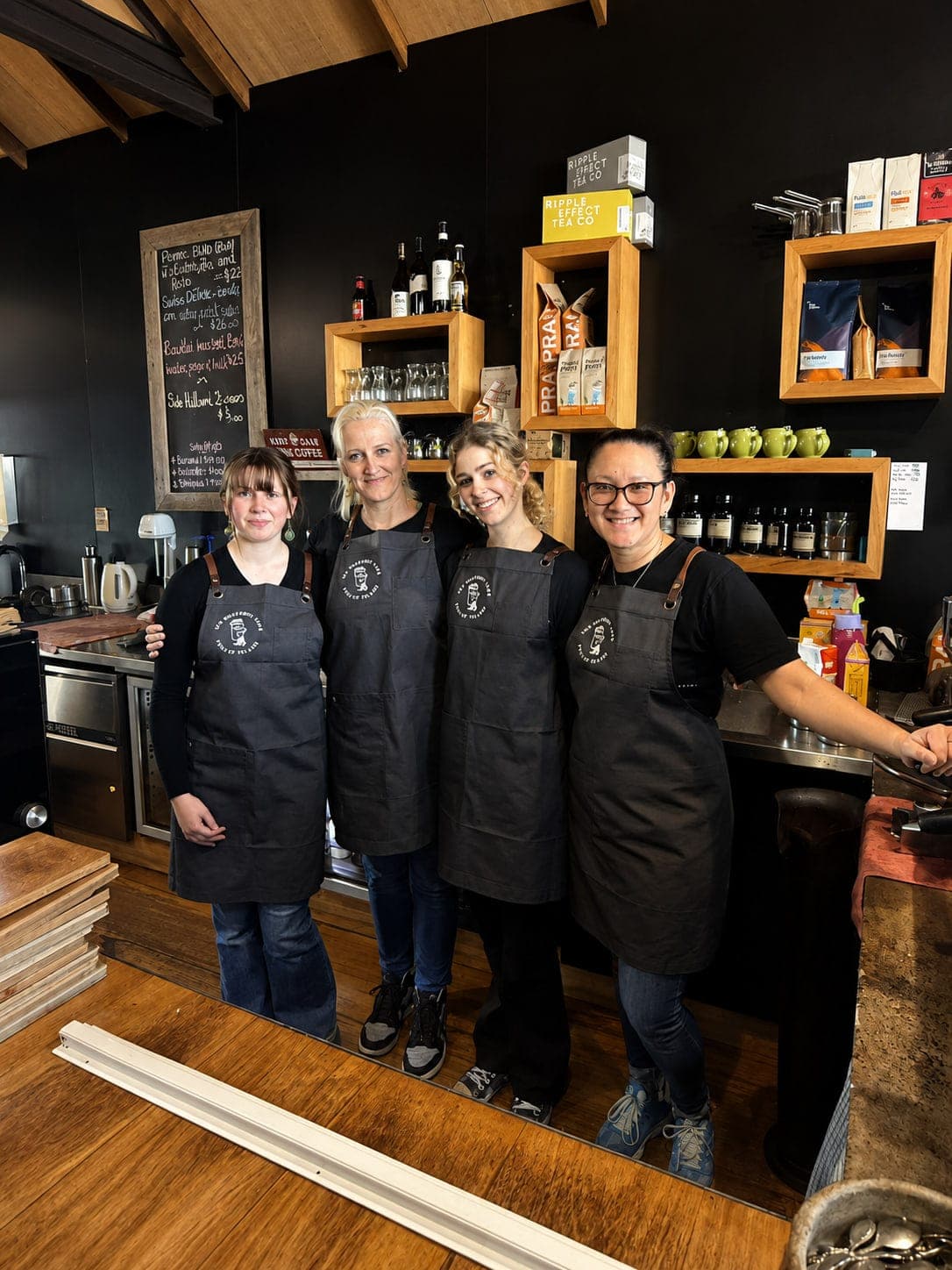 Four members of the team standing together behind the counter, aprons on, ready for service